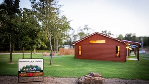 A wooden cabin with a signboard advertising Serenity Lane Cabins, featuring a booking option and a contact number. - Private Cabin Villege with Hot Tubs & Firepit for 16 people (Cherokee County)