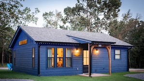 A blue house with a porch, large windows, and a well-maintained lawn. - Private Cabin Villege with Hot Tubs & Firepit for 16 people (Cherokee County)
