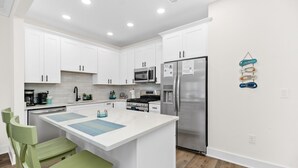 Een moderne keuken met witte kastjes, roestvrijstalen apparatuur en een centraal eiland met zitplaatsen.