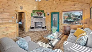 Un acogedor interior de cabaña de madera con chimenea, asientos cómodos y un televisor.