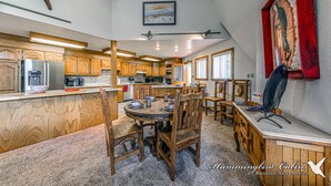Eine geräumige Küche mit Holzausstattung, ein Essbereich mit rundem Tisch und Stühlen sowie ein großes Bild an der Wand.
