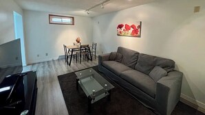 Un soggiorno moderno con un divano grigio, un tavolino in vetro e un'area pranzo con tavolo e sedie.