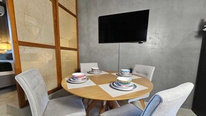 A dining area with a round table, four chairs, and a flat-screen TV mounted on the wall. - Casa Frida Kahlo (Tulum)