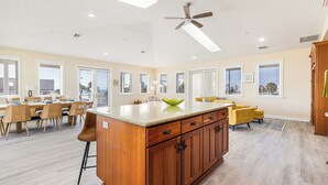 A spacious kitchen with a large island, wooden cabinets, and a ceiling fan.