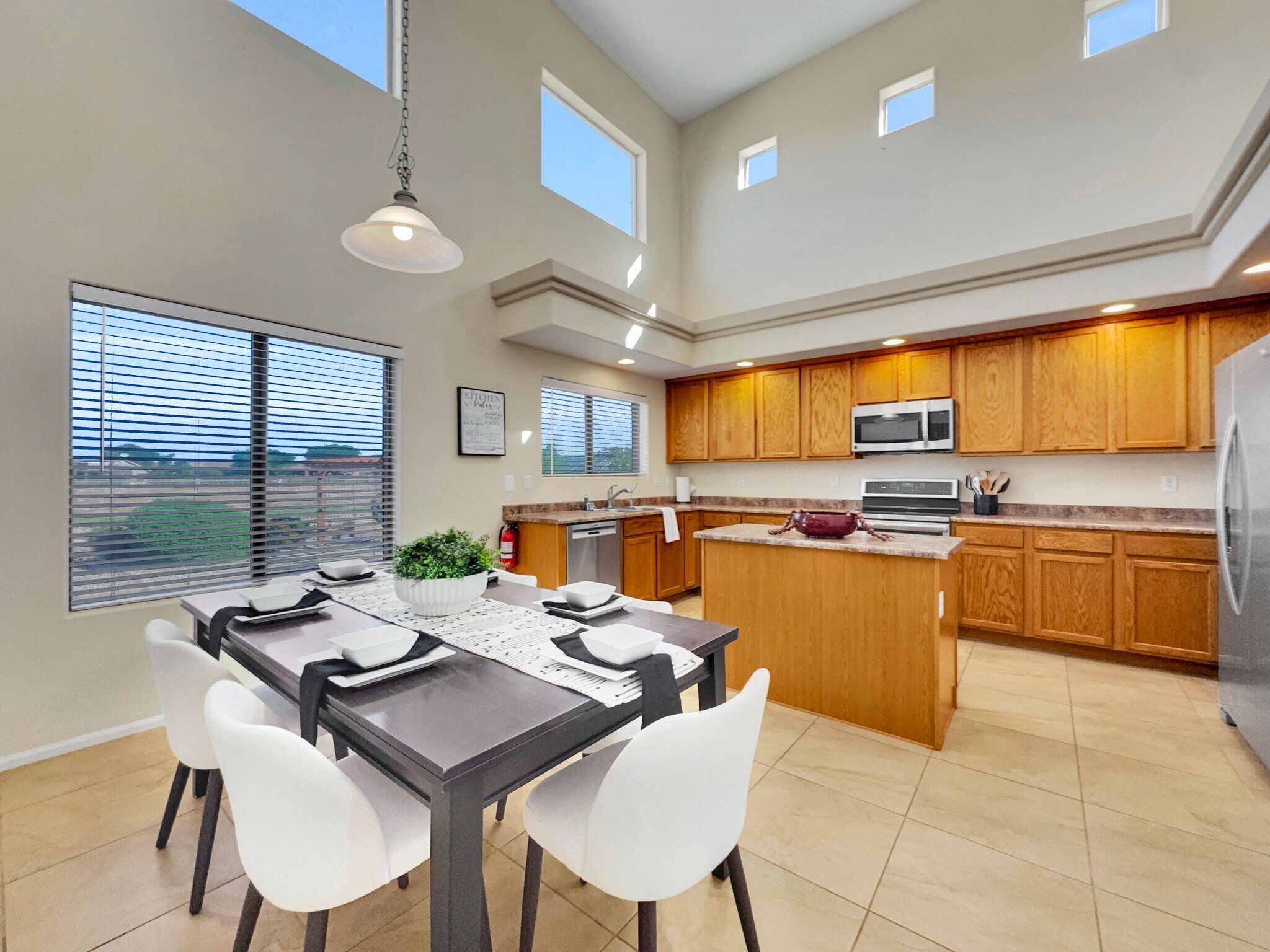 A modern kitchen with wooden cabinets, a central island, and a dining area with a table and chairs.