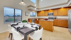 Une cuisine moderne avec des meubles en bois, un îlot central et un coin repas comprenant une table et des chaises.