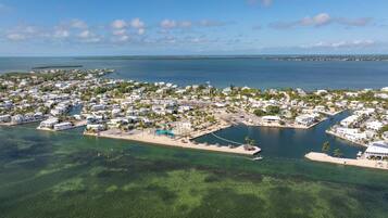 An aerial view of a coastal residential area with houses, clear blue water, and a marina.