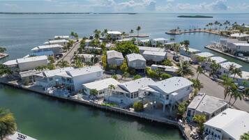 A coastal residential area with houses adjacent to a marina, featuring clear views of the water and distant islands.