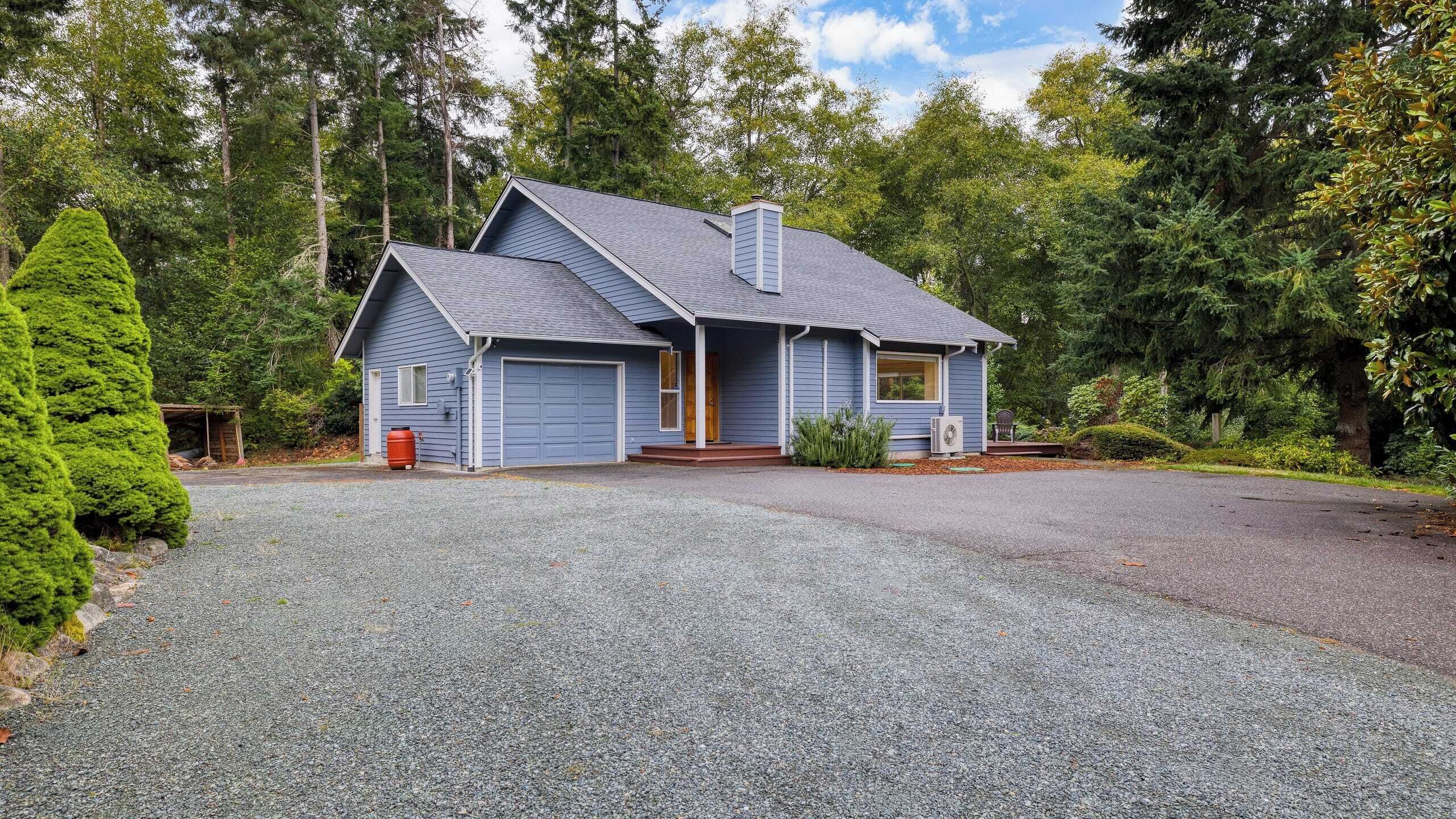 A two-story house with a grey roof, a front porch, and a garage.