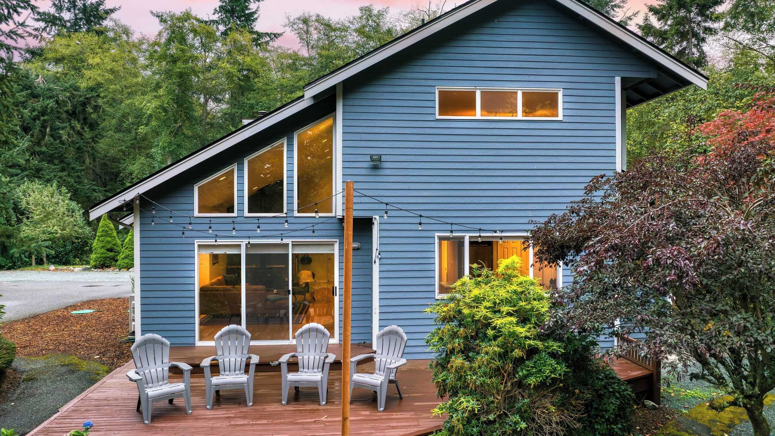 A two-story house with a deck, large windows, and a garden.