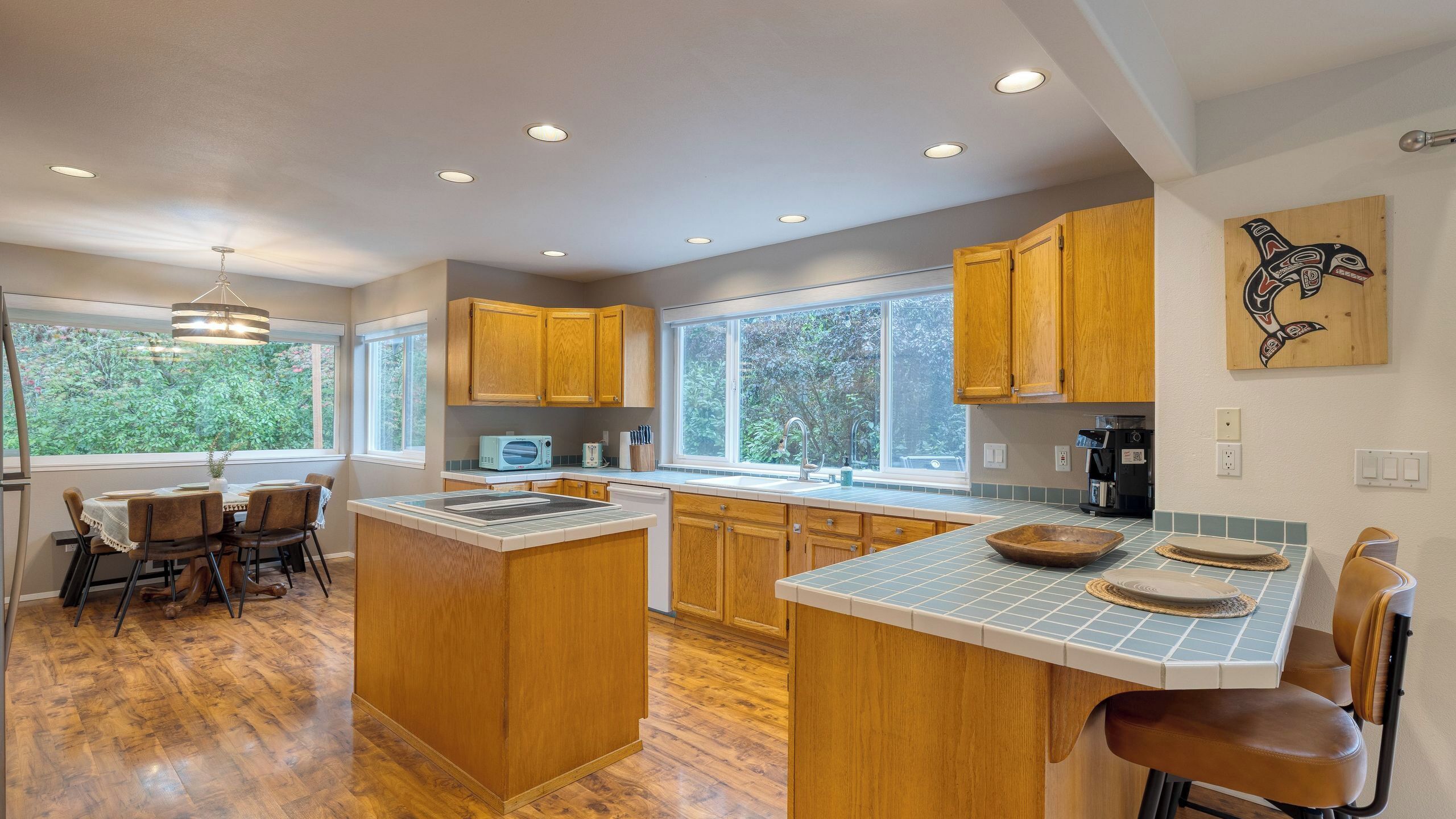 Una cocina moderna con armarios de madera, una isla central y un comedor con vistas a zonas verdes.