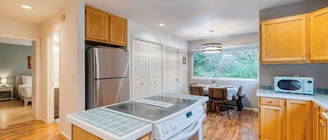 A modern kitchen with wooden cabinets, a stainless steel refrigerator, a built-in oven, and a microwave on the countertop.