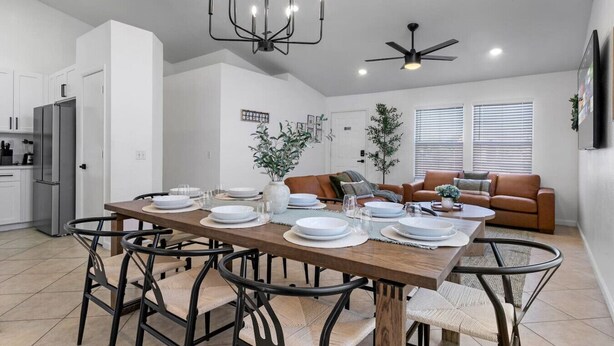 Una cocina moderna con armarios blancos, una mesa de comedor para cuatro personas y un ventilador de techo.
