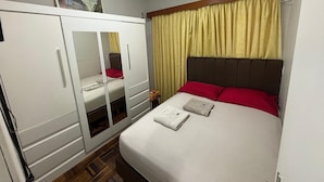 A bedroom with a bed, a wardrobe, and an air conditioning unit.