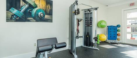 A gym with exercise equipment, a bench, and a wall-mounted painting.