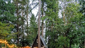 A cabin with a fire pit and two red Adirondack chairs in a forest setting. - Epic A Frame (Granite Falls)