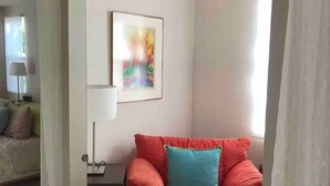 A room with a red sofa, a small table with a lamp, and a colorful abstract painting on the wall. - Private Sedona retreat with private hot tub (Sedona)