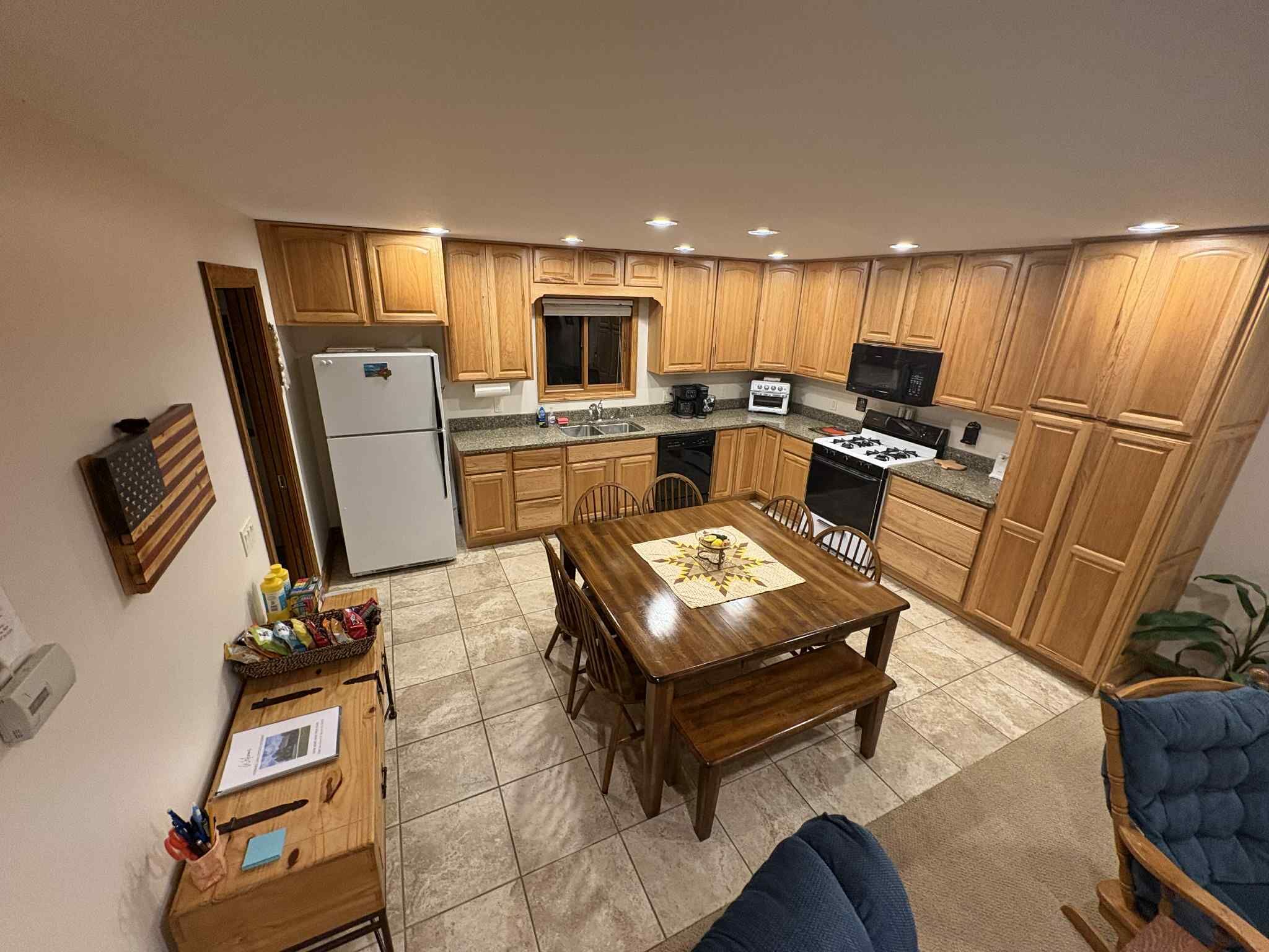 Une cuisine compacte dotée de meubles en bois, d’un réfrigérateur, d’une cuisinière, d’un four à micro-ondes et d’une table à manger avec des chaises.