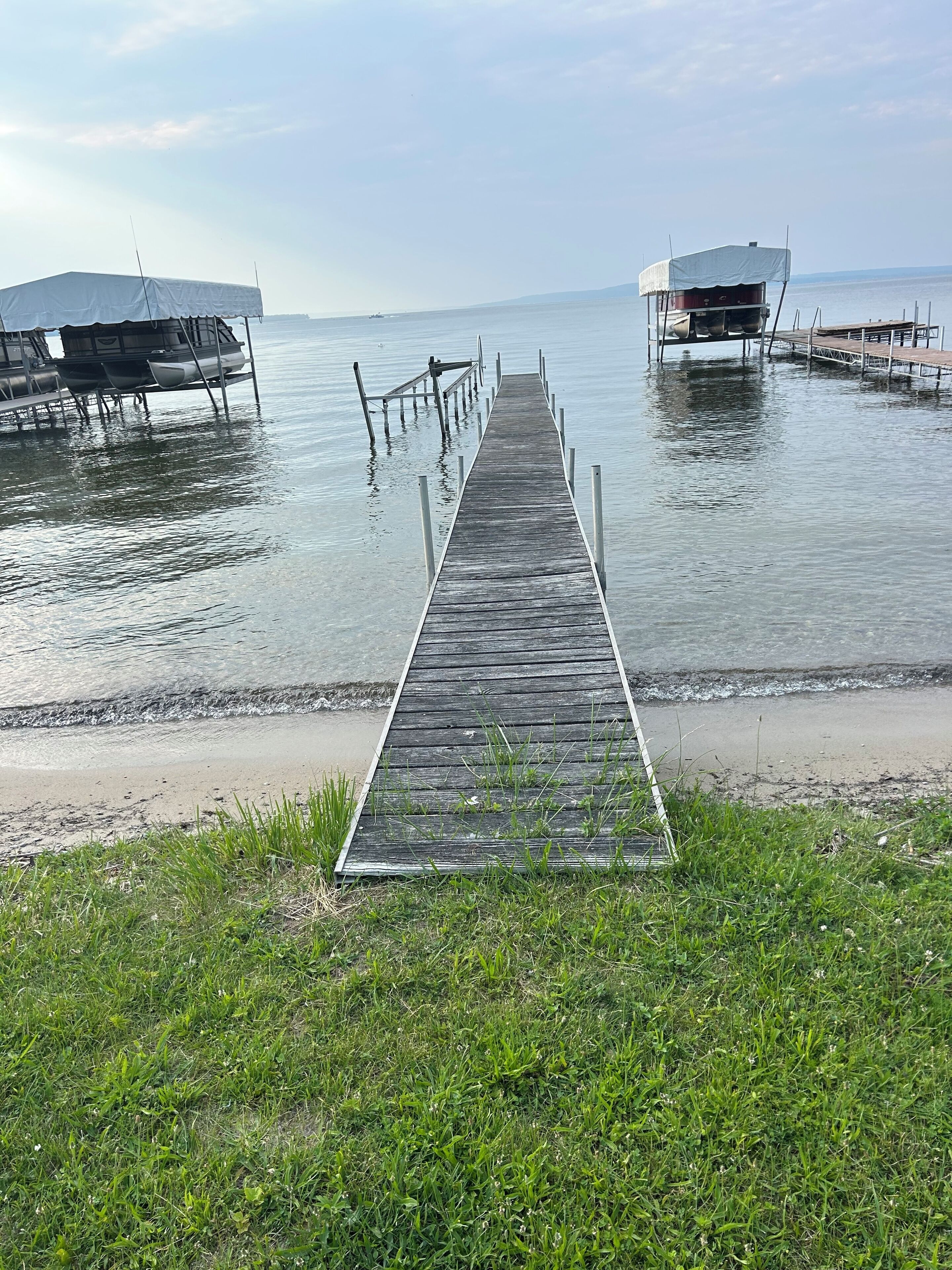 A wooden pier leading to a dock with two covered boat launch ramps.