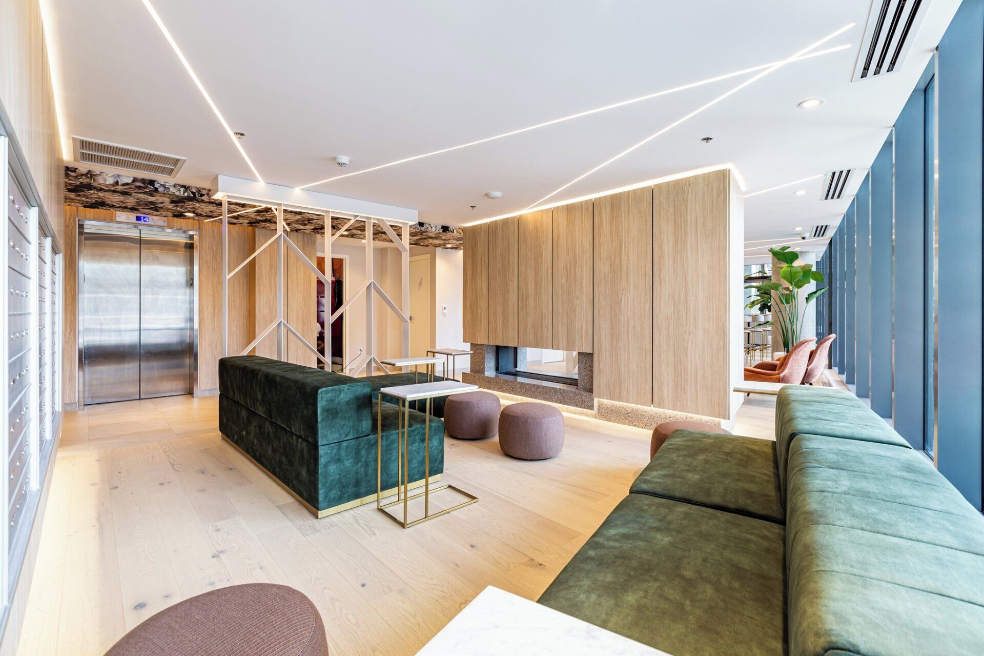 A modern living room with a sofa, ottomans, and a coffee table. There is a wooden cabinet and a television.