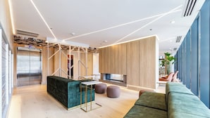 Een moderne woonkamer met een bank, poefs en een salontafel. Er is een houten kast en een televisie.