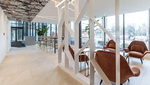 Een modern interieur met een glazen wand, een trap en zitgedeeltes.