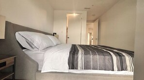 Ein Schlafzimmer mit einem Bett, einem Nachttisch und einer Tür zu einem Badezimmer.