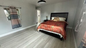 Un dormitorio con cama, ventilador de techo y ventana con cortinas.