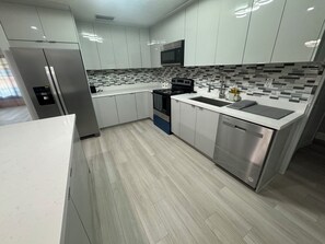 A modern kitchen with white cabinets, a stainless steel refrigerator, a microwave, a stove, and a dishwasher. - 4-bedroom house in amazing Clewiston near Marina  (Clewiston)