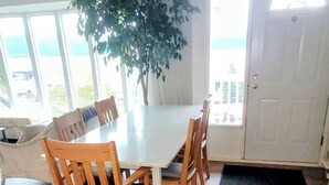 En matplats med ett stort bord och trästolar, en krukväxt och utsikt genom en dörr.