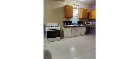 Een oven, een kookplaat, kookgerei, borden en bestek, eettafels