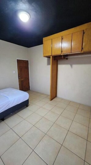 Une chambre à coucher avec un lit, une armoire en bois et une porte.
