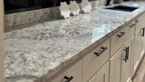 Een keuken met witte kasten, granieten aanrecht en een zwarte kraan.