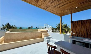 An outdoor patio with a wooden ceiling, a bar area, and a view of the ocean.