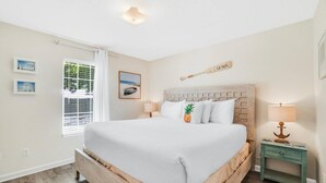 Ein Schlafzimmer mit einem großen Bett, einem Nachttisch mit Lampe, einem Fenster mit Jalousien und einem an der Wand befestigten Baseballschläger.
