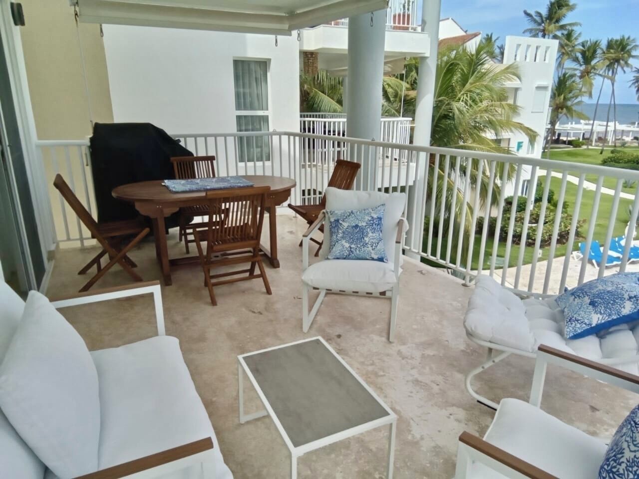 Un balcon avec une table, des chaises et une petite table d’appoint.
