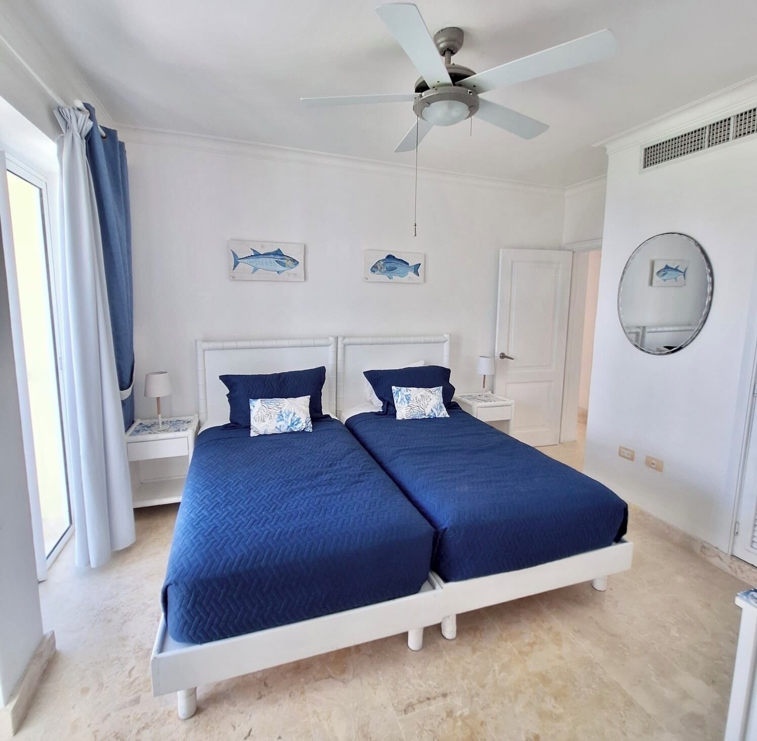 Une chambre avec deux lits, un ventilateur de plafond et des œuvres d’art accrochées aux murs.
