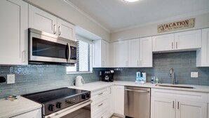 Una cocina moderna con armarios blancos, electrodomésticos de acero inoxidable y un salpicadero.