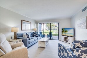 Un salon avec un canapé, une table basse, un téléviseur et une vue sur l’extérieur.