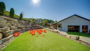 A well-maintained grassy area with a stone wall, a white building with large windows, and a clear blue sky.