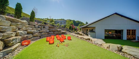 A well-maintained grassy area with a stone wall, a white building with large windows, and a clear blue sky.