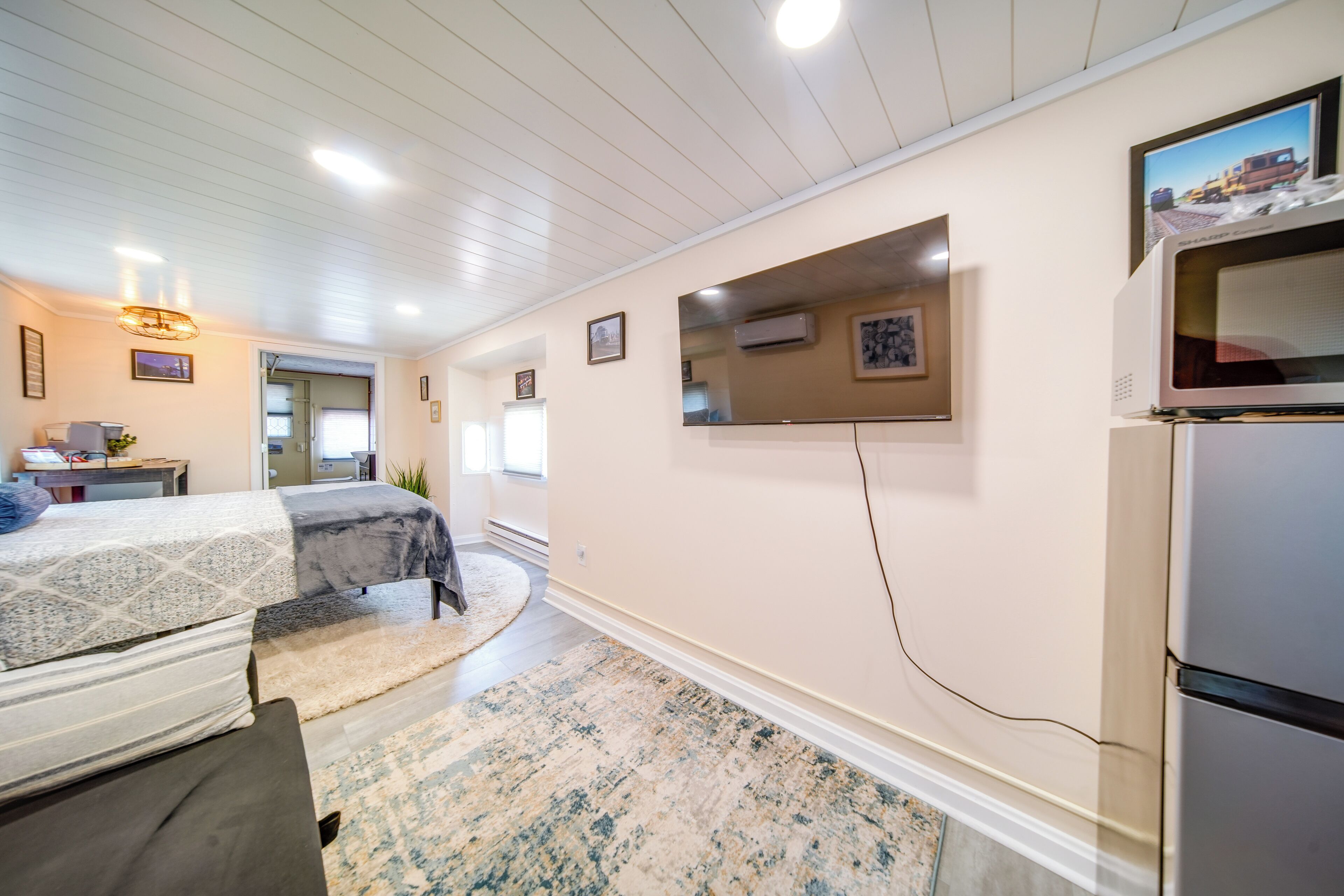 Ett hotellrum med en säng, ett skrivbord, en stol, en tv och ett kylskåp.