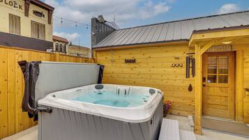 Un bâtiment en bois avec une porte en bois sur laquelle est écrit « BIENVENUE » et un jacuzzi à l’avant.