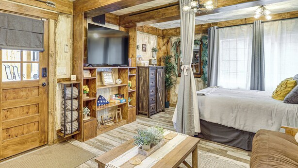 Un interior acogedor de madera, con una cama, un televisor y una estantería con libros y adornos.