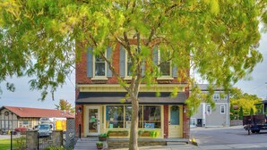 A two-story building with a brick facade, large windows, and a tree in front. - Walk to Marina: Dog-friendly Lake Ontario Studio (Sackets Harbor)