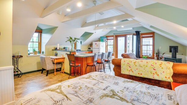 A cozy attic bedroom with a large bed, a desk, and a dining area. - Walk to Marina: Dog-friendly Lake Ontario Studio (Sackets Harbor)