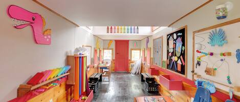 Un cuarto de juegos infantil, muy colorido, con muebles de madera, decoraciones llamativas y material educativo.