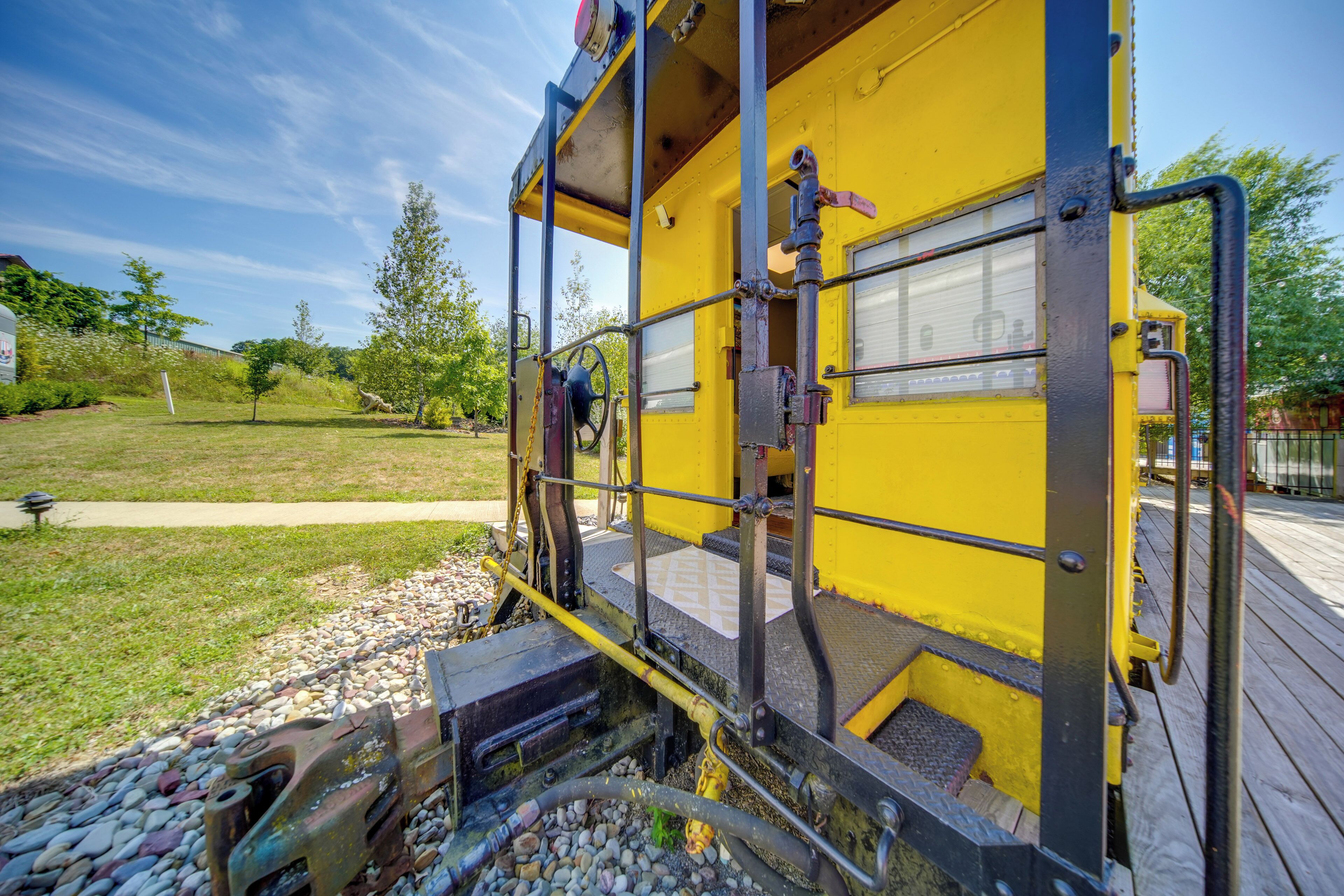 A yellow train car with a metal exterior, a window, and a door.