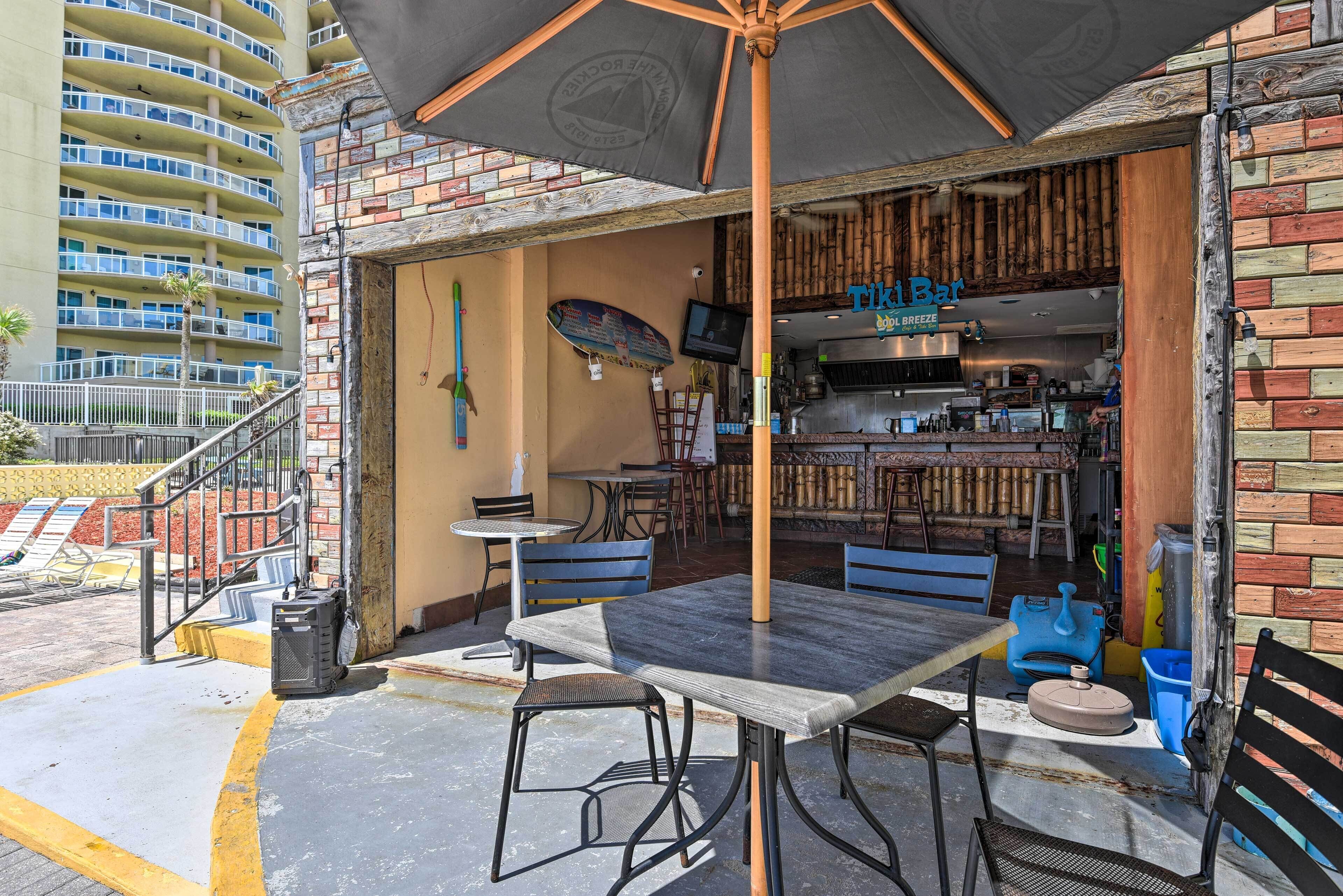 An outdoor seating area with a table and chairs, a large umbrella, and a bar with a sign reading "Tik Bar".