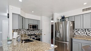A modern kitchen with granite countertops, stainless steel appliances, and grey cabinetry.